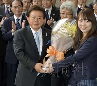 12月18日，高票當(dāng)選東京都新知事的豬瀨直樹正式到任。圖為豬瀨從政府職員手中接過花束。(共同社)