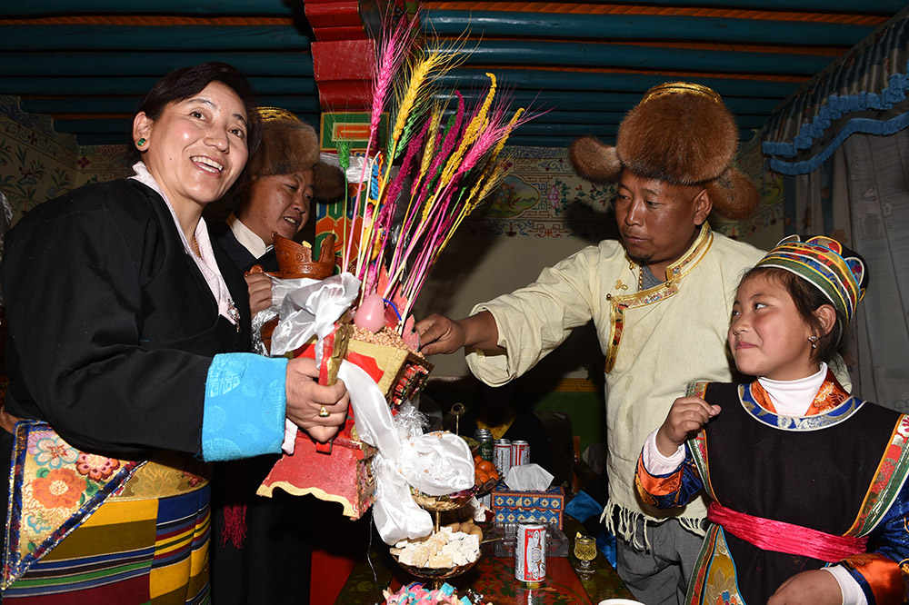 2月27日，拉薩市城關(guān)區(qū)阿壩林卡社區(qū)居民央拉（左）向鄰居敬獻(xiàn)“切瑪”。